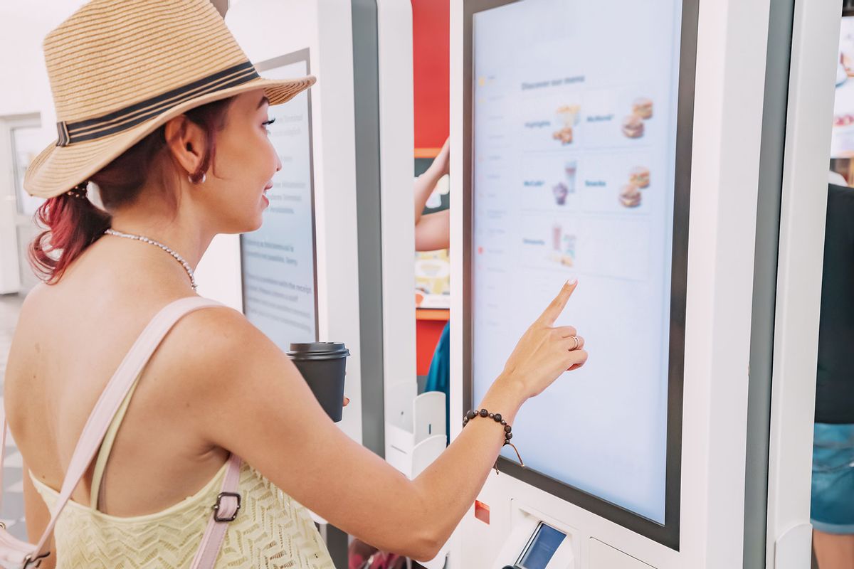 A female customer uses a touchscreen self-service kiosk to order at a fast food restaurant. (Getty Images/)